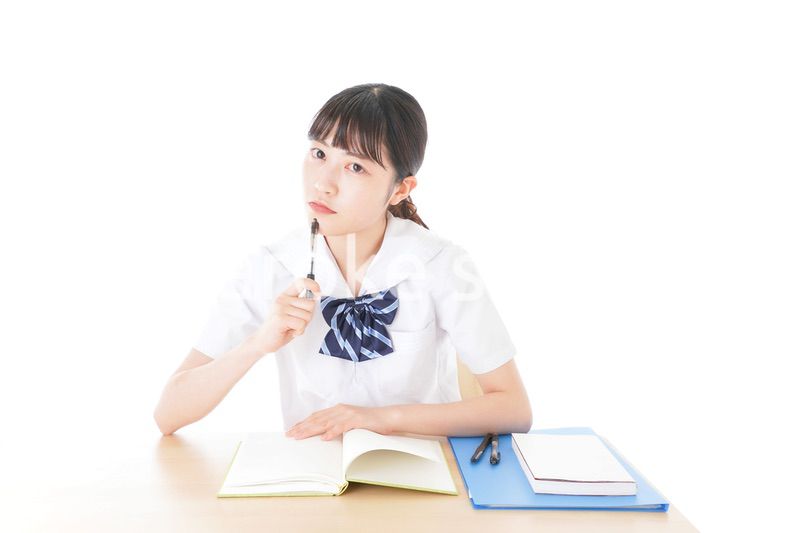 机で勉強をする制服姿の女子学生