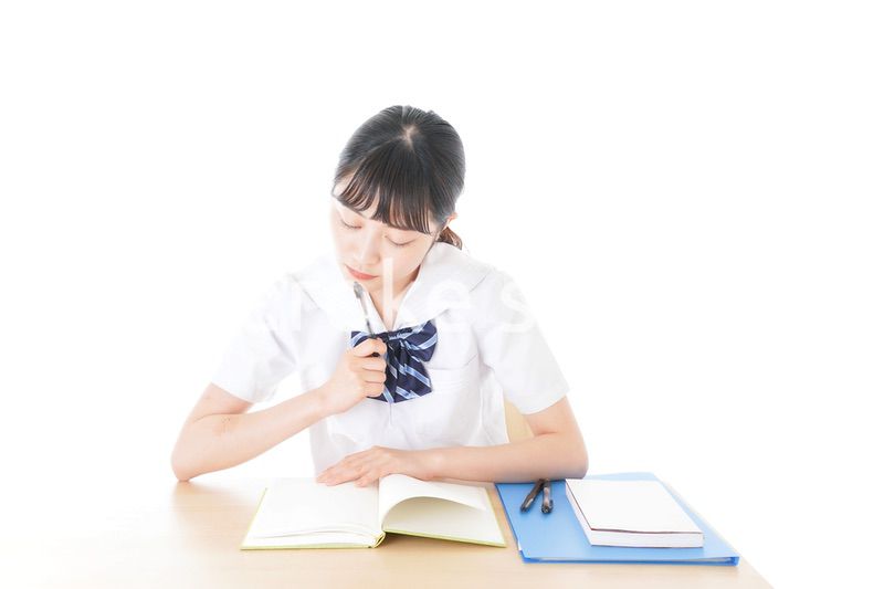 机で勉強をする制服姿の女子学生