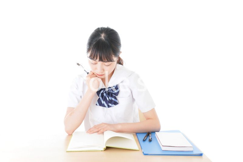 机で勉強をする制服姿の女子学生