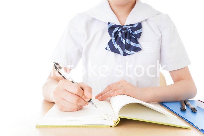 机で勉強をする制服姿の女子学生