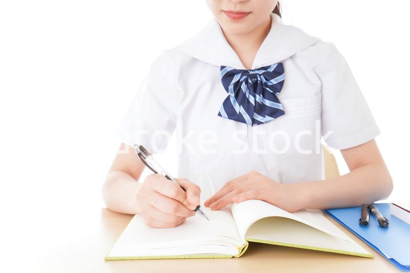 机で勉強をする制服姿の女子学生