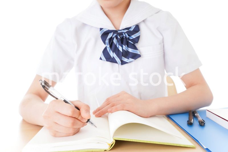机で勉強をする制服姿の女子学生