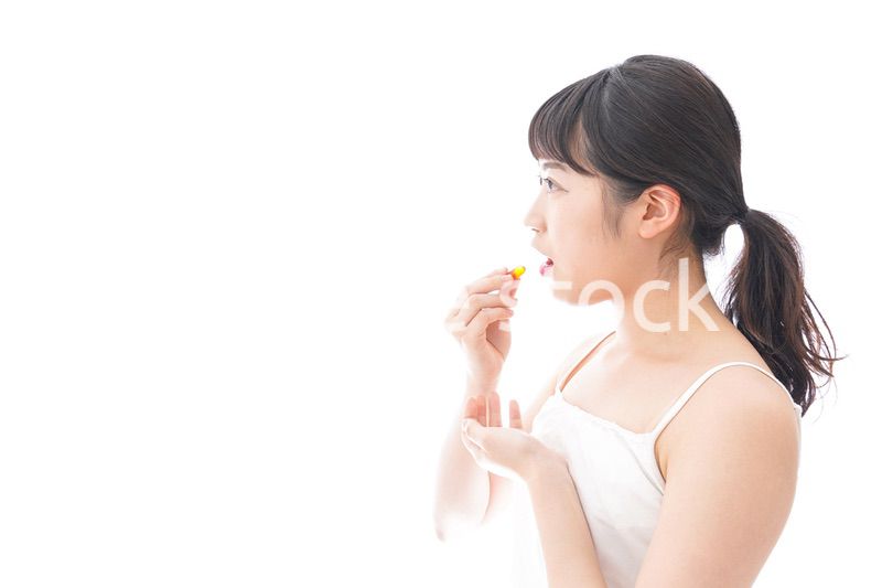 薬・サプリメントを飲む若い女性