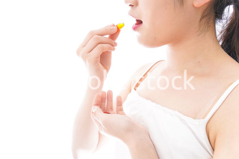 薬・サプリメントを飲む若い女性