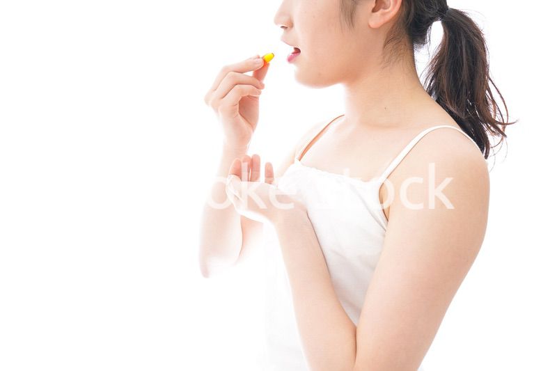 薬・サプリメントを飲む若い女性