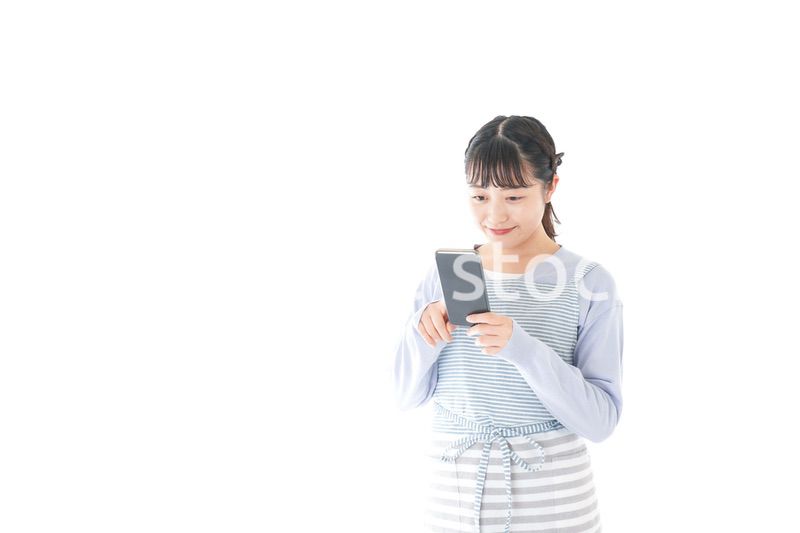 笑顔でスマートフォンを使う若い主婦