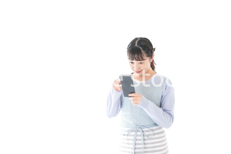 笑顔でスマートフォンを使う若い主婦