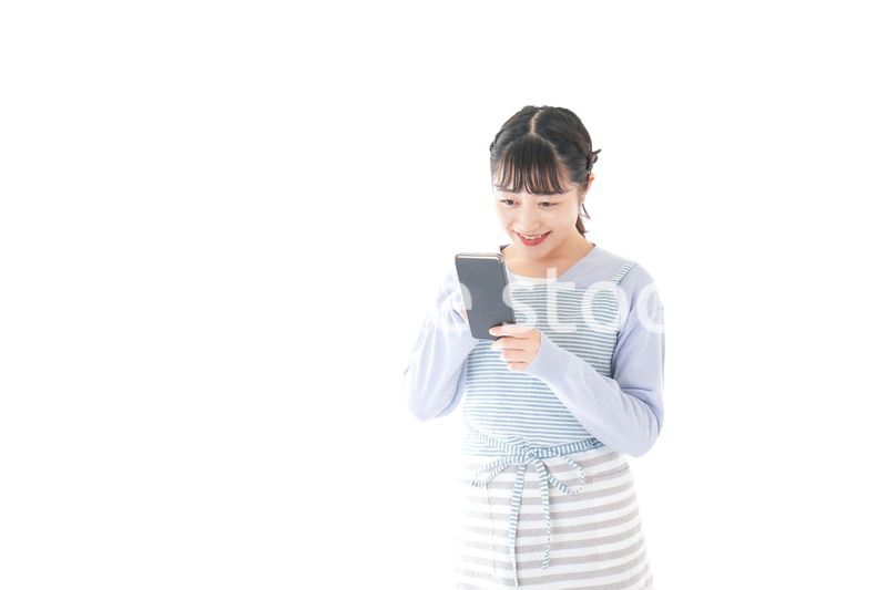 笑顔でスマートフォンを使う若い主婦