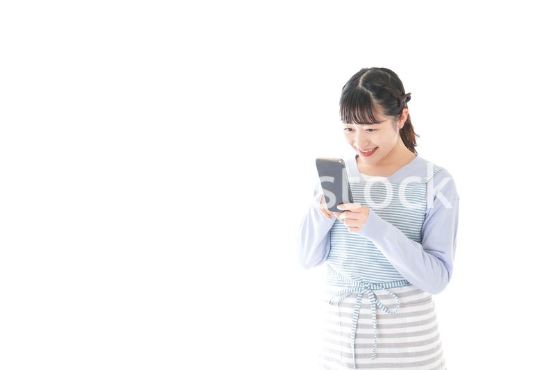 笑顔でスマートフォンを使う若い主婦