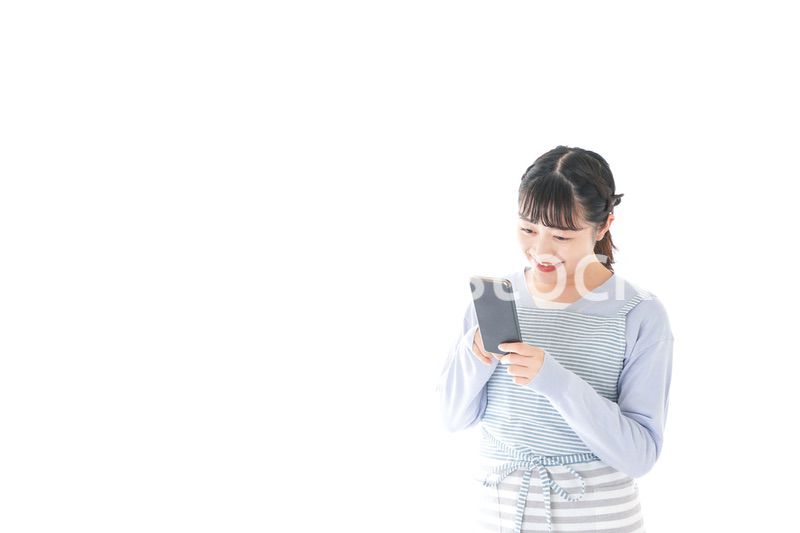 笑顔でスマートフォンを使う若い主婦