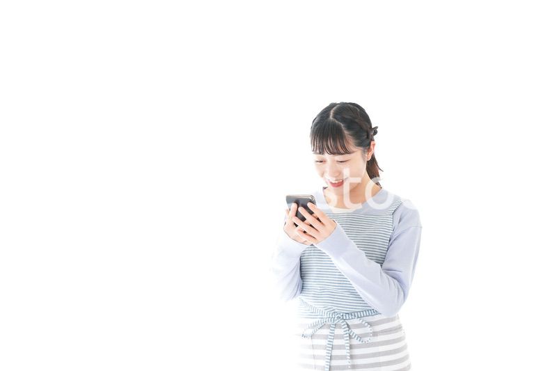 笑顔でスマートフォンを使う若い主婦