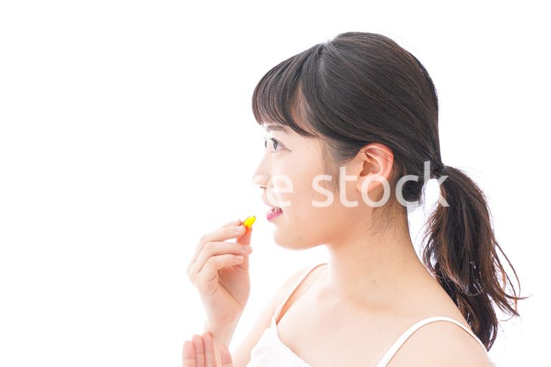 薬・サプリメントを飲む若い女性