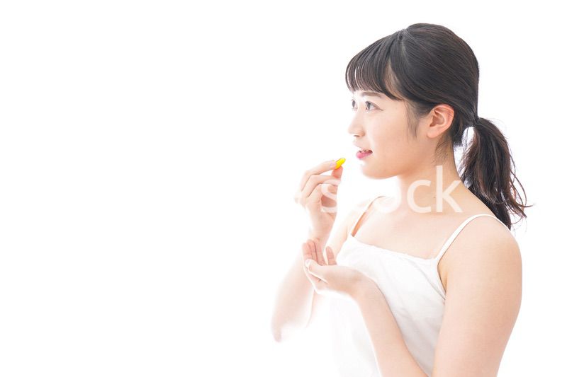 薬・サプリメントを飲む若い女性