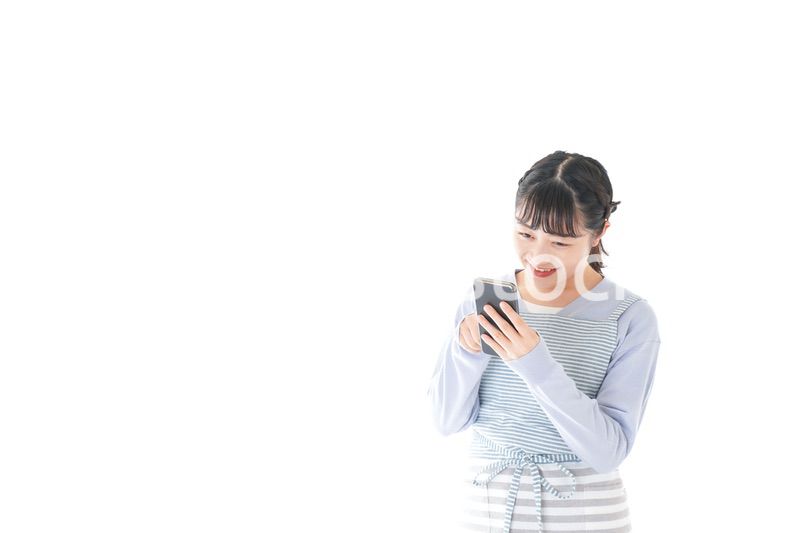 笑顔でスマートフォンを使う若い主婦