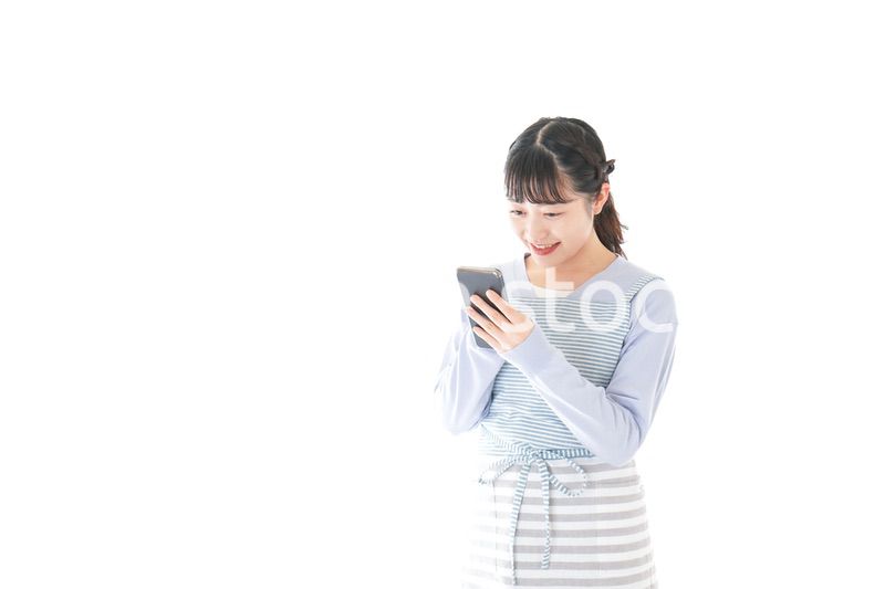 笑顔でスマートフォンを使う若い主婦