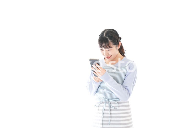 笑顔でスマートフォンを使う若い主婦