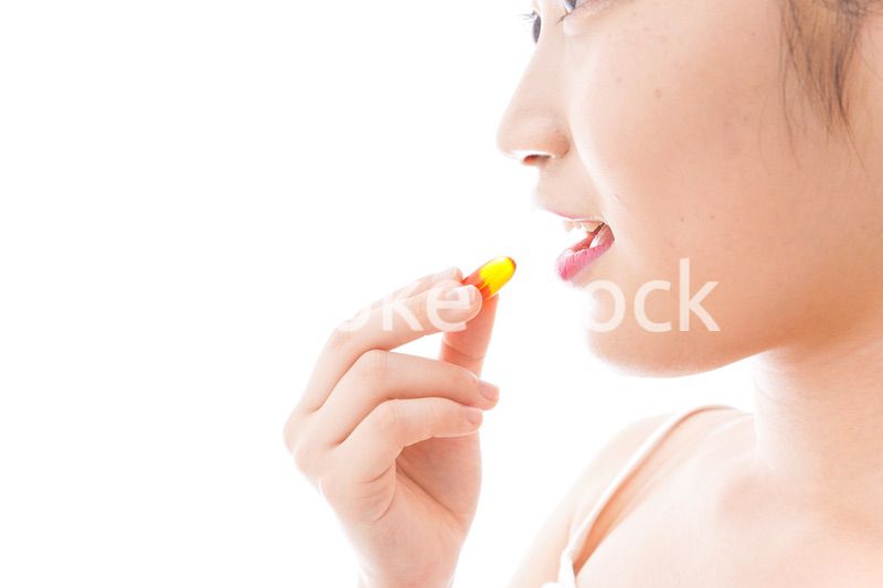 薬・サプリメントを飲む若い女性