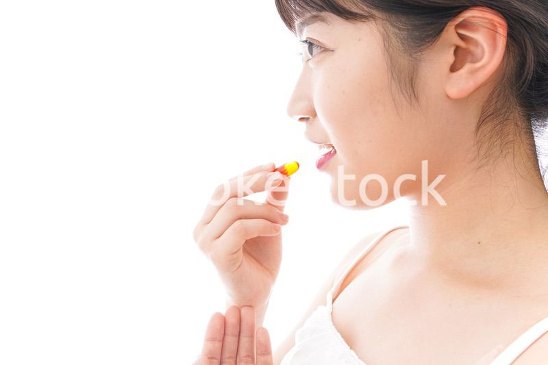 薬・サプリメントを飲む若い女性