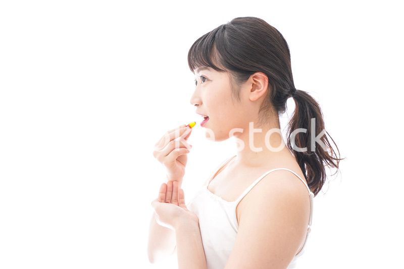 薬・サプリメントを飲む若い女性
