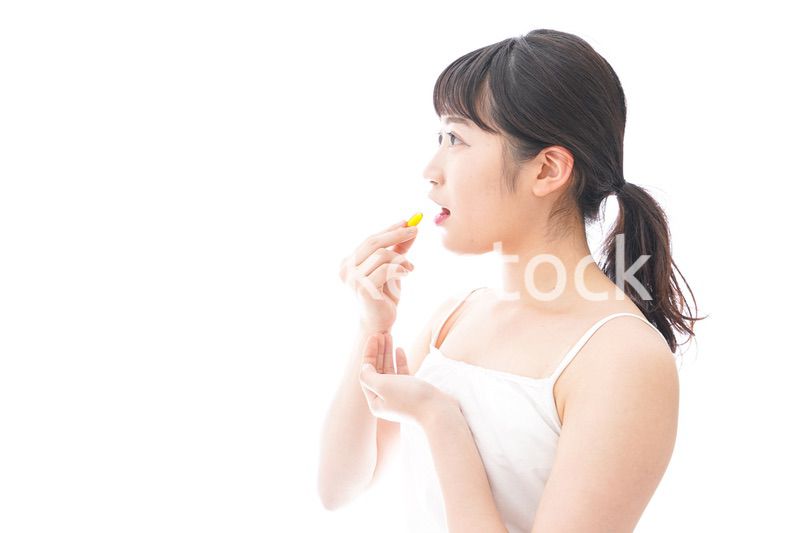 薬・サプリメントを飲む若い女性
