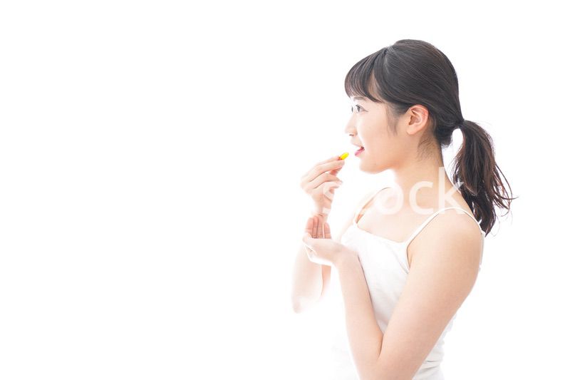 薬・サプリメントを飲む若い女性