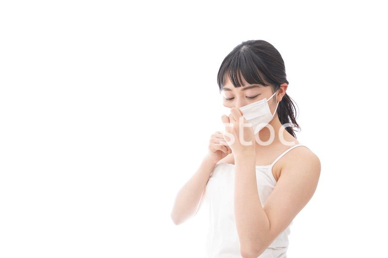 花粉症・風邪・インフルエンザに苦しみマスクをする若い女性