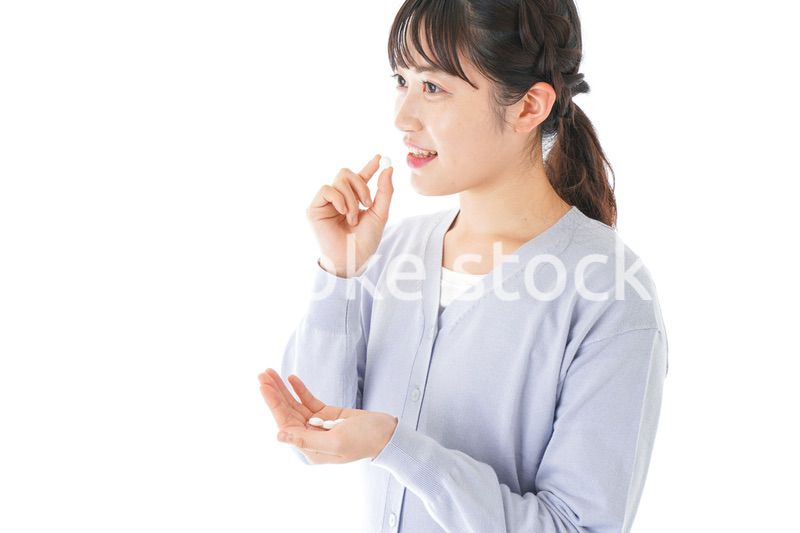 薬・サプリメントを服用する若い女性