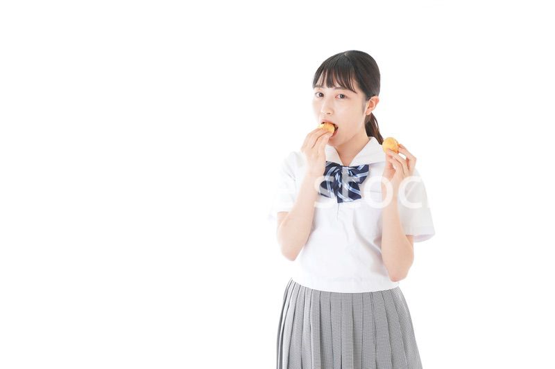 おやつを食べる制服姿の女子学生