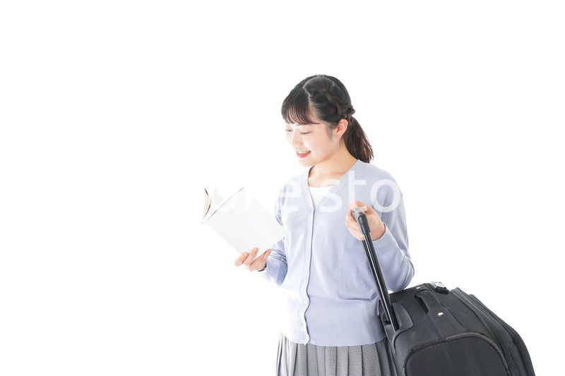 ガイドブックを持ち一人旅をする若い女性