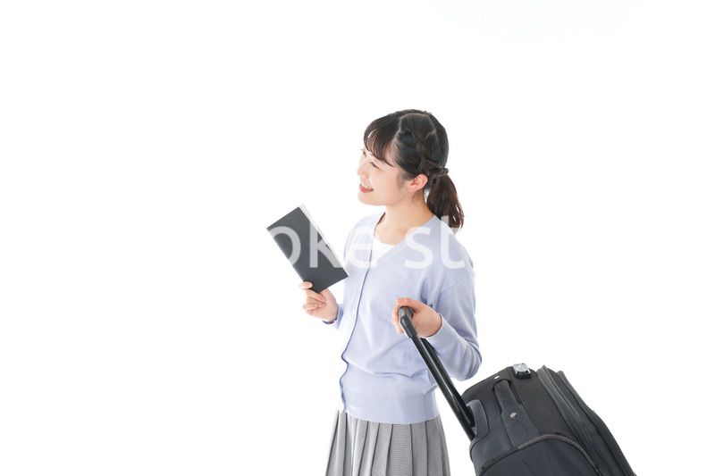 ガイドブックを持ち一人旅をする若い女性