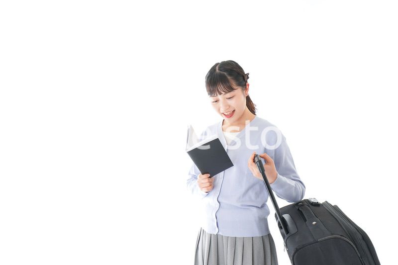 ガイドブックを持ち一人旅をする若い女性