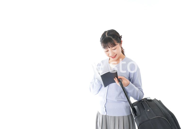 ガイドブックを持ち一人旅をする若い女性