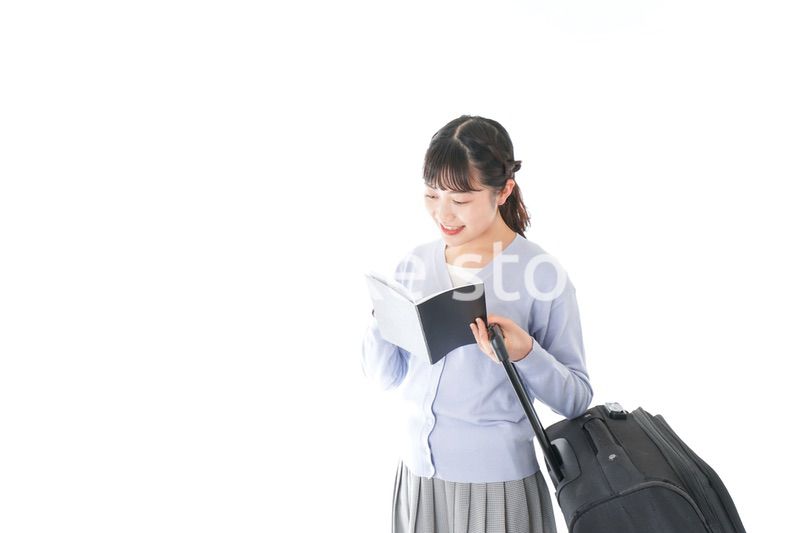 ガイドブックを持ち一人旅をする若い女性