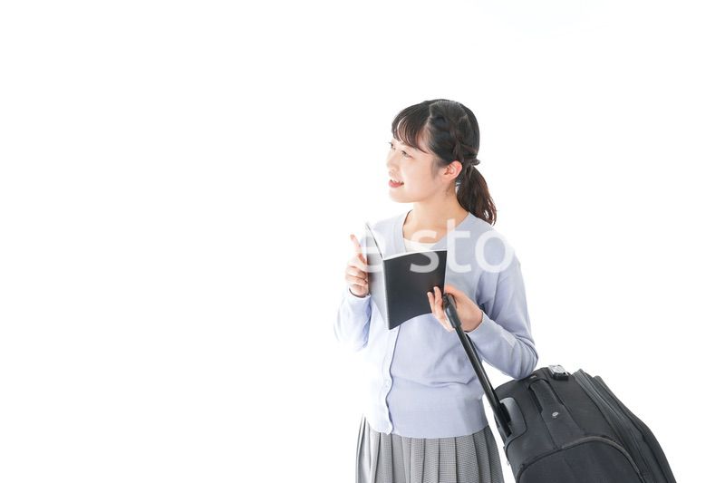 ガイドブックを持ち一人旅をする若い女性