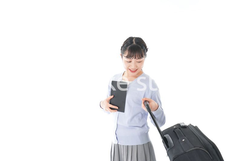 ガイドブックを持ち一人旅をする若い女性