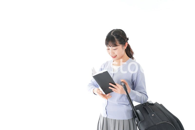 ガイドブックを持ち一人旅をする若い女性