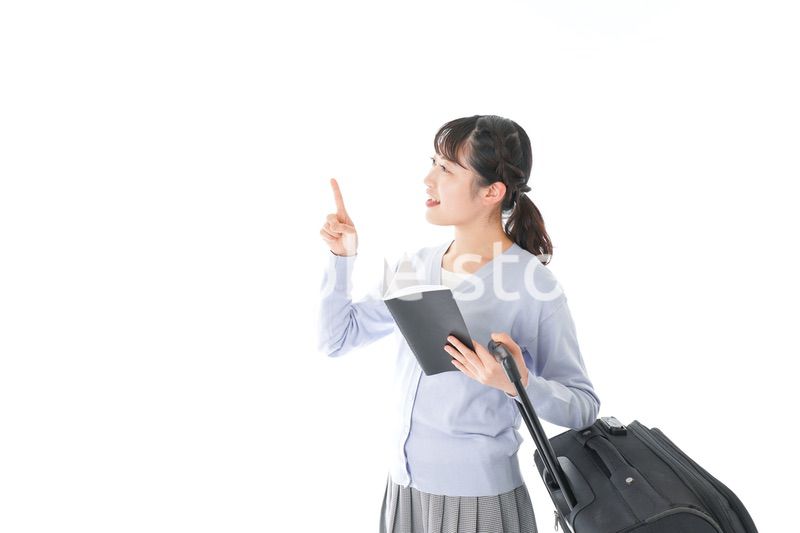 ガイドブックを持ち一人旅をする若い女性