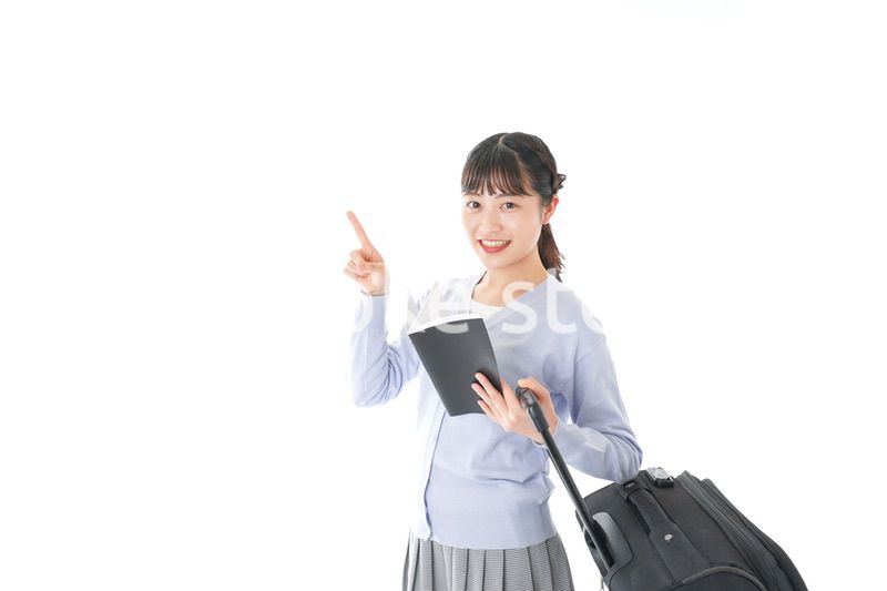 ガイドブックを持ち一人旅をする若い女性