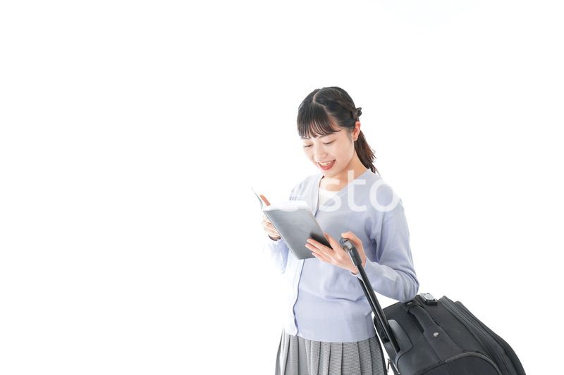 ガイドブックを持ち一人旅をする若い女性