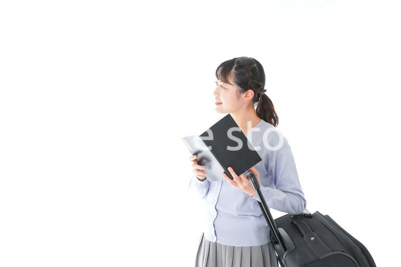 ガイドブックを持ち一人旅をする若い女性