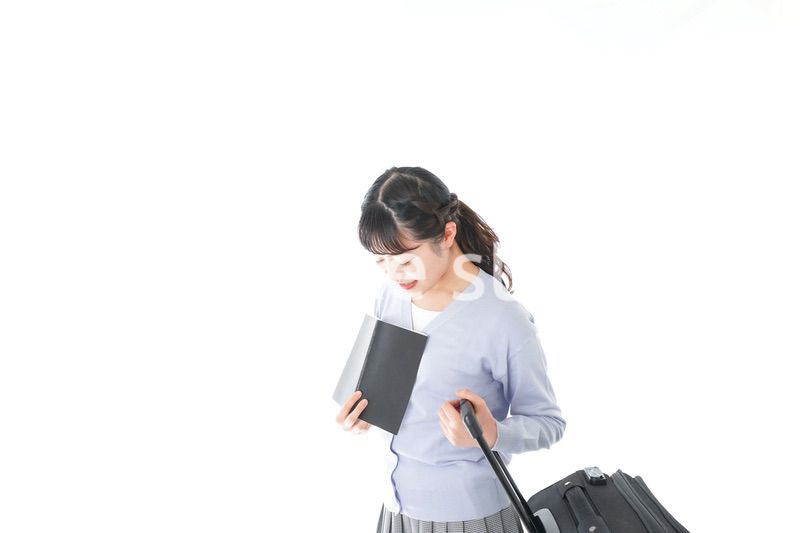 ガイドブックを持ち一人旅をする若い女性