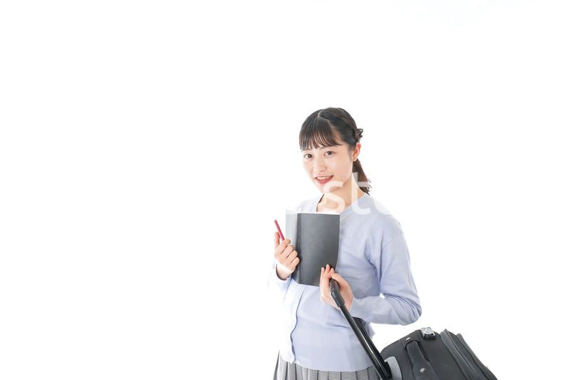 ガイドブックを持ち一人旅をする若い女性