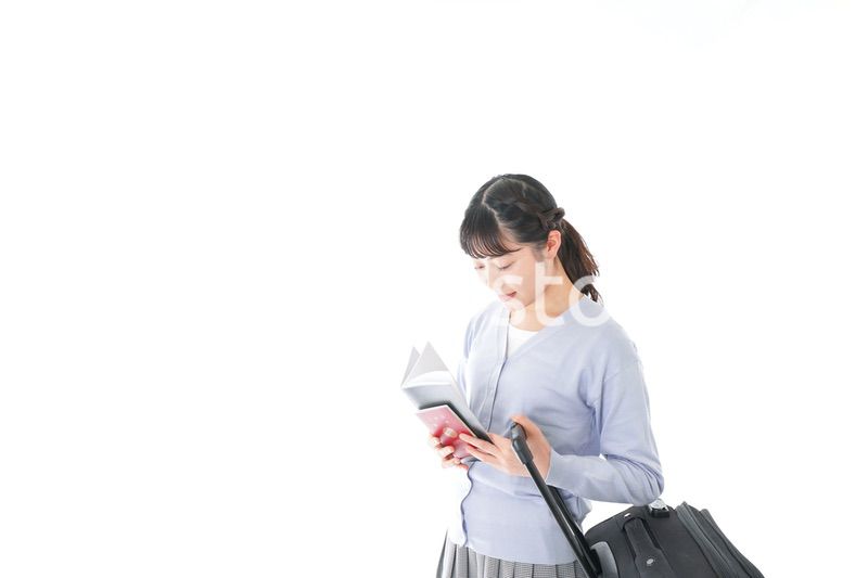 ガイドブックを持ち一人旅をする若い女性