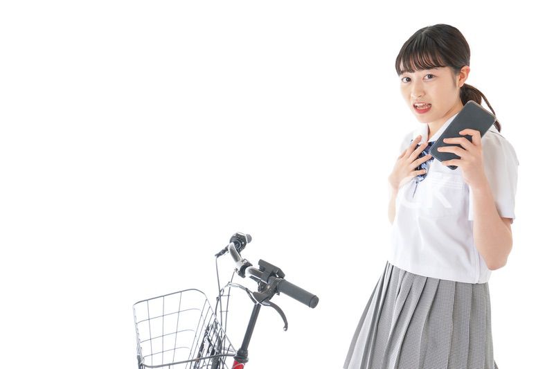 自転車でスマホを使う若い学生