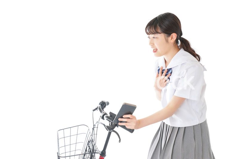 自転車でスマホを使う若い学生