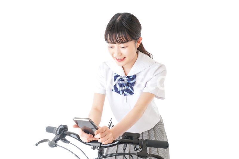 自転車でスマホを使う若い学生