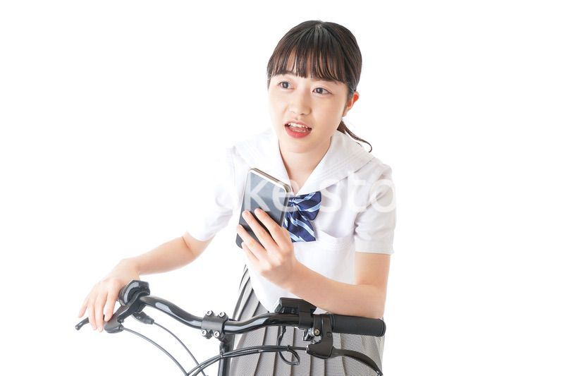 自転車でスマホを使う若い学生