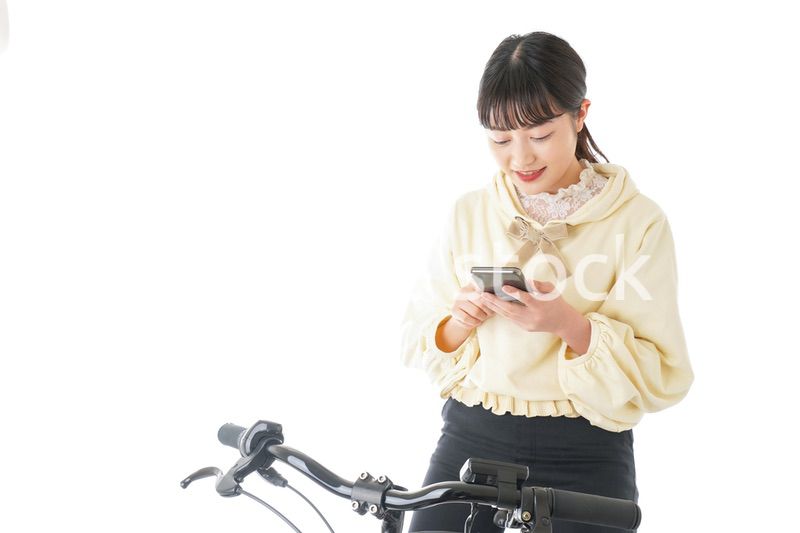 自転車でスマホを使う若い女性