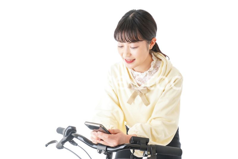 自転車でスマホを使う若い女性
