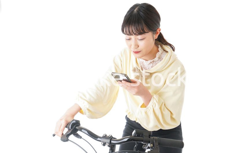 自転車でスマホを使う若い女性
